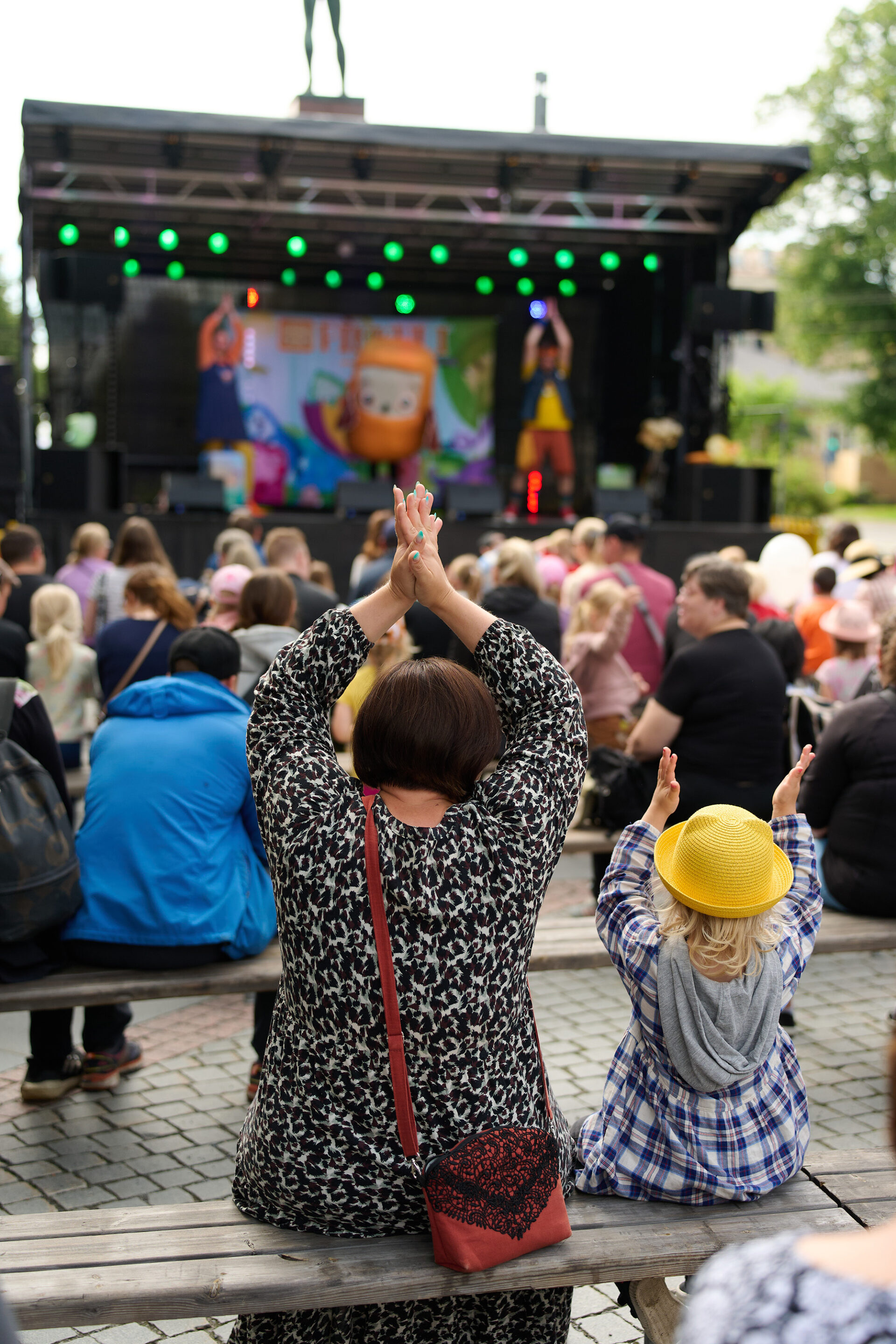 Yleisö katsoo lavaesitystä ja taputtaa käsiä ilmaan.